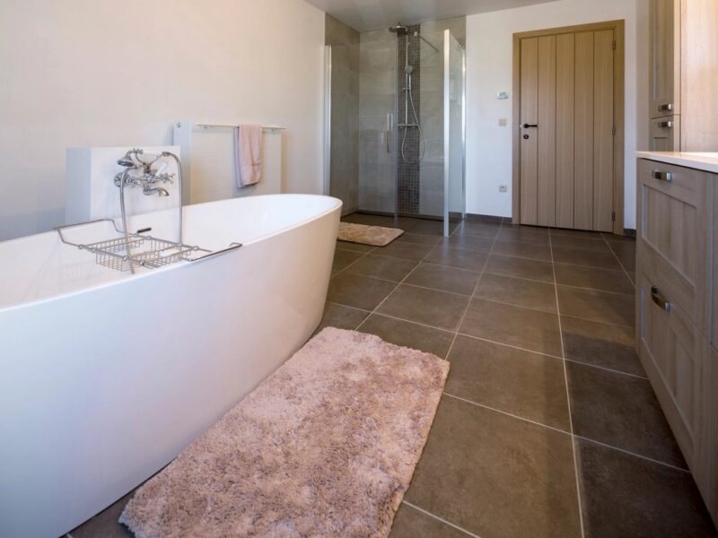 Badkamer met vrijstaand bad en tegelvloer