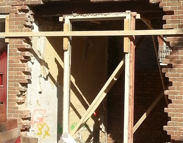 Doorbraak in bakstenen muur met houten stempels