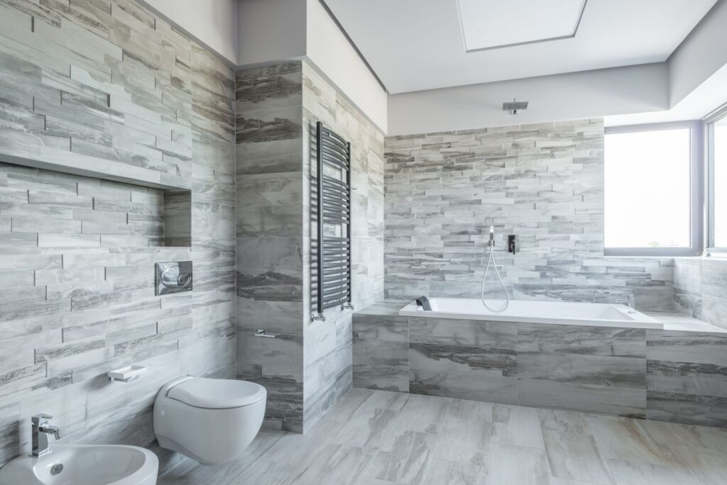 Badkamer met ligbad en grijze natuursteentegels