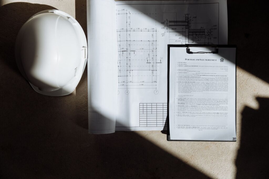 Bouwhelm, tekening en documenten op een tafel in het zonlicht