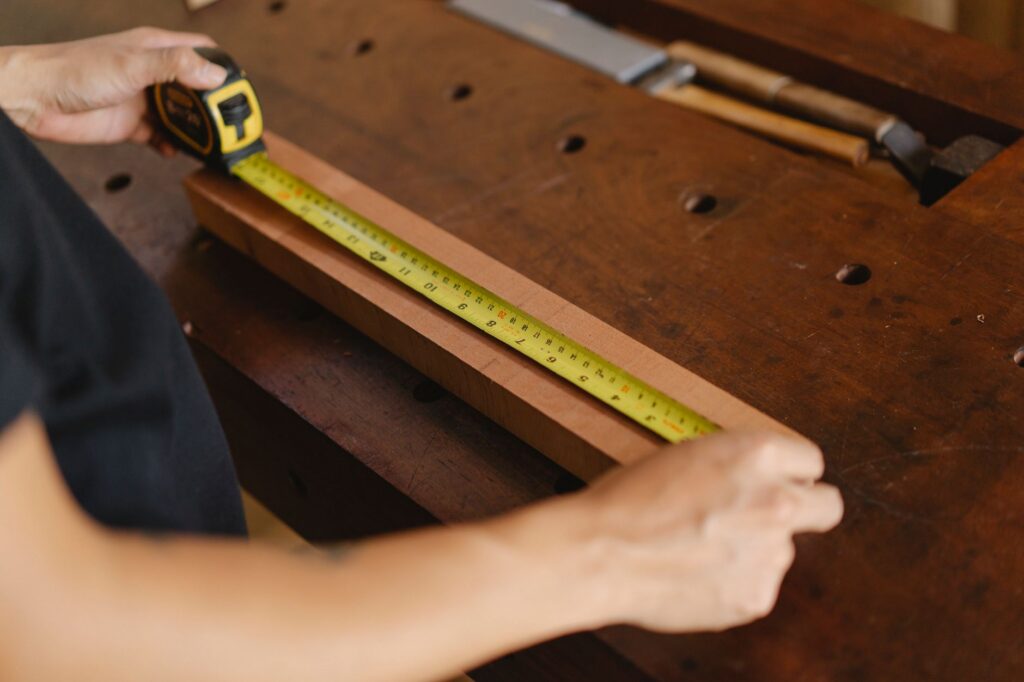 Timmerman meet een plank op de werkbank met een gele rolmaat