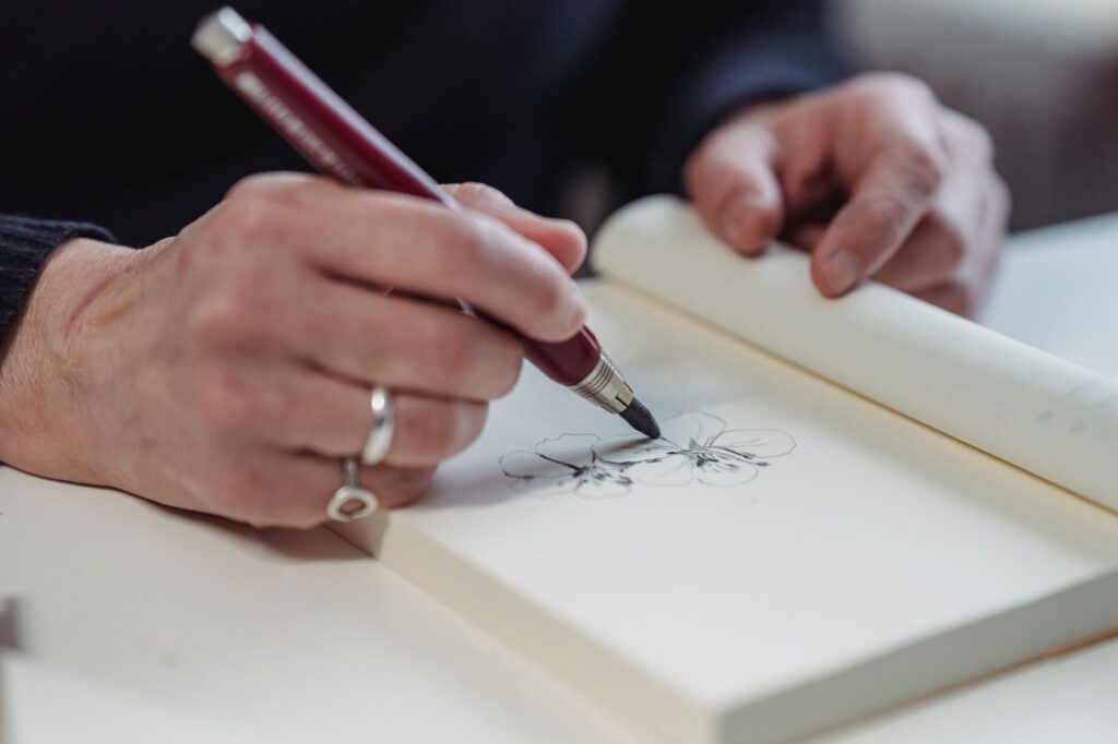 Hand tekent met een vulpen in een schetsboek