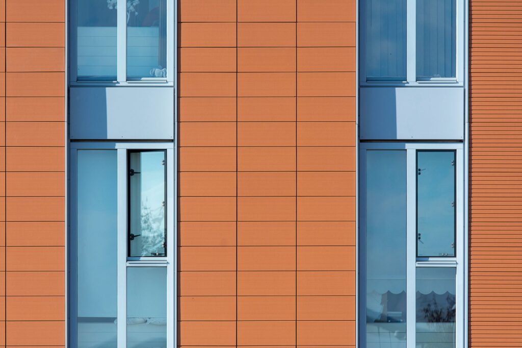 Gevel met oranje panelen en hoge ramen