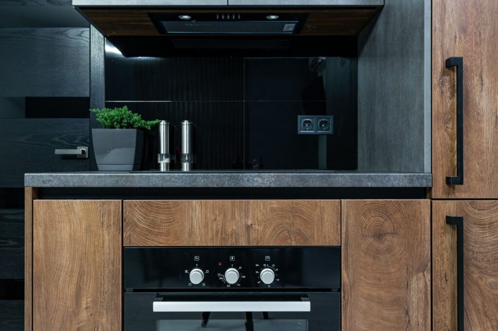 Keuken met houten kastjes, een zwarte wand en een inbouwoven