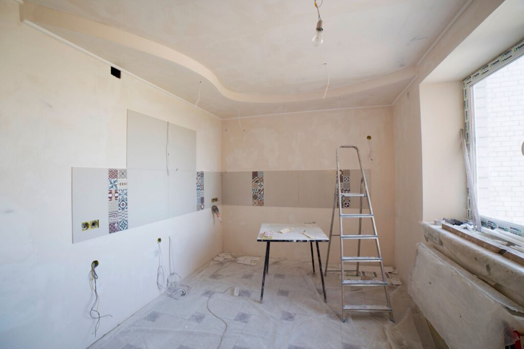 Lege kamer in verbouwing met trapladder en open leidingen in de wand
