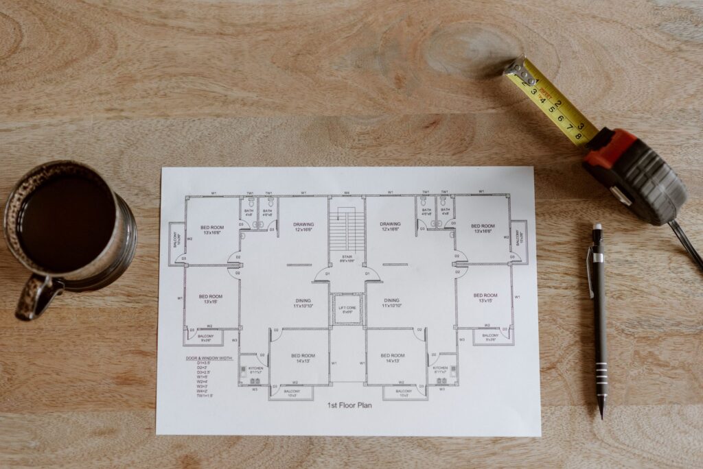 Plattegrond met rolmaat, pen en koffie op een houten tafel