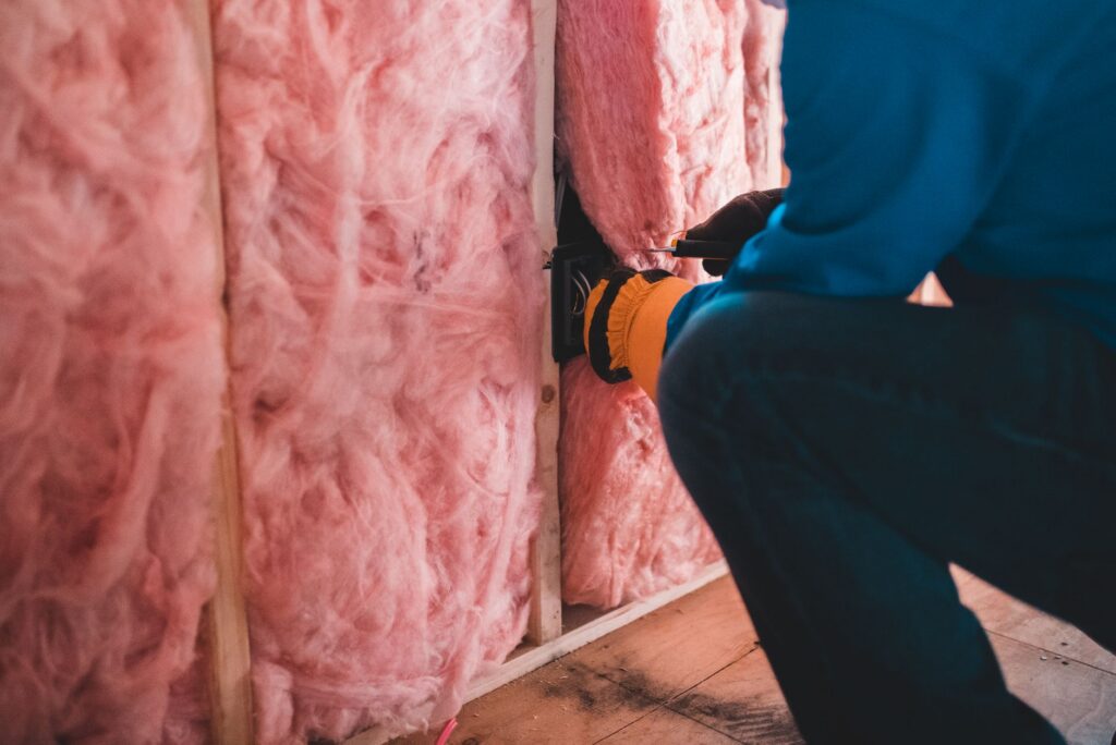 Vakman met handschoenen plaatst roze isolatiewol