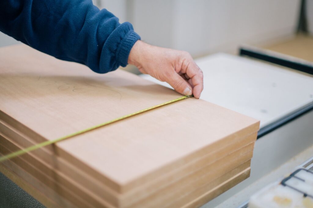 Hand meet houten platen op met een rolmaat